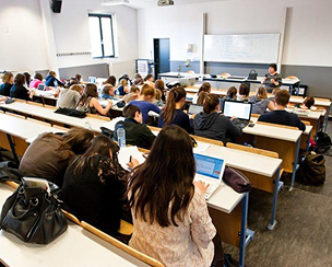 une salle de classe (amphithéâtre) avec des éleves et dans le fond un tableau